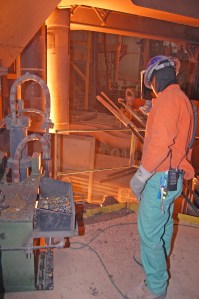 A worker checks the temperature of the molten steel