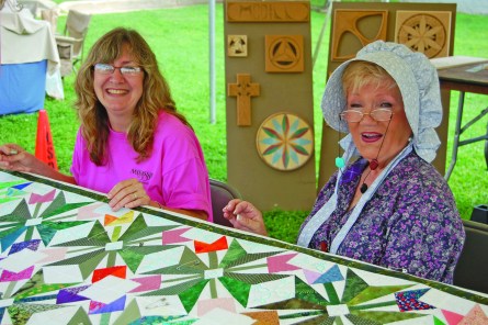 Carla Formel and Watana Cantrell of the Possum Town Quilters work together at the Artisians Alley on Saturday.